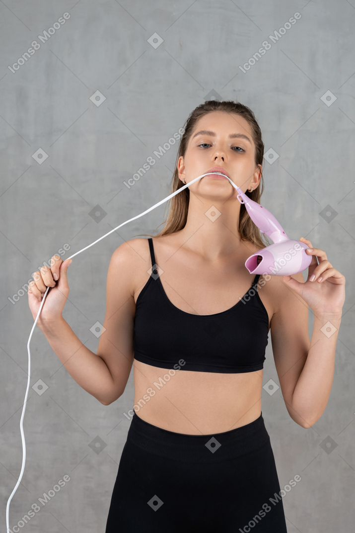 Bela jovem mordendo o fio do secador de cabelo