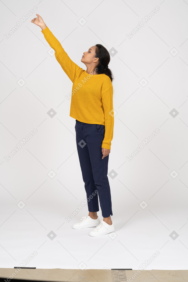 Side view of a girl in casual clothes pointing up with finger