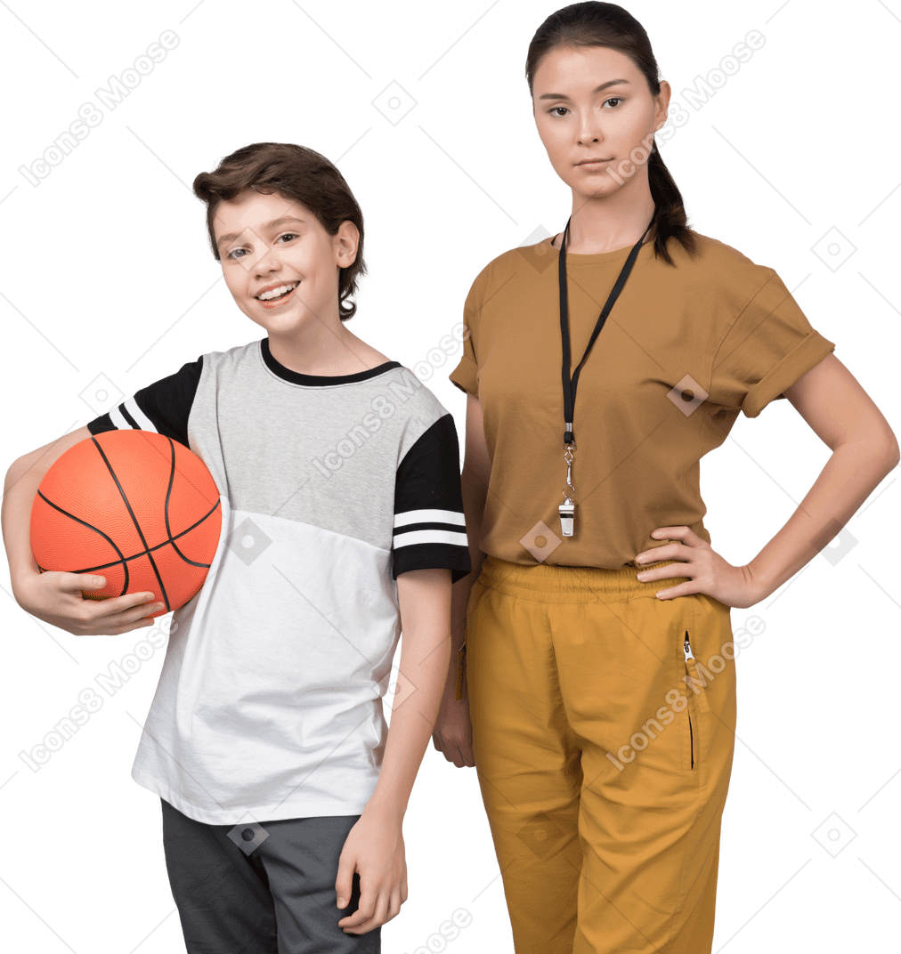 Profesora de pe y su alumno sosteniendo una pelota de baloncesto