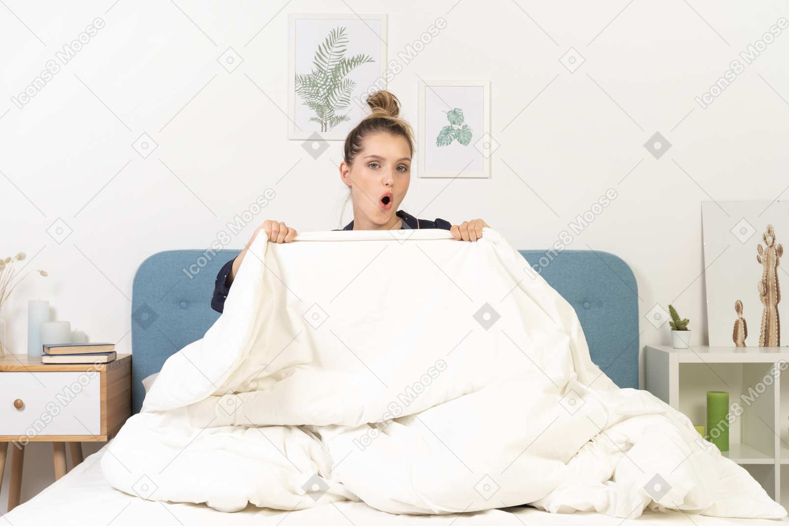 Front view of a surprised young woman in pajamas hiding behind the blanket staying in bed