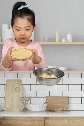 A little girl holding a pie in front of her face