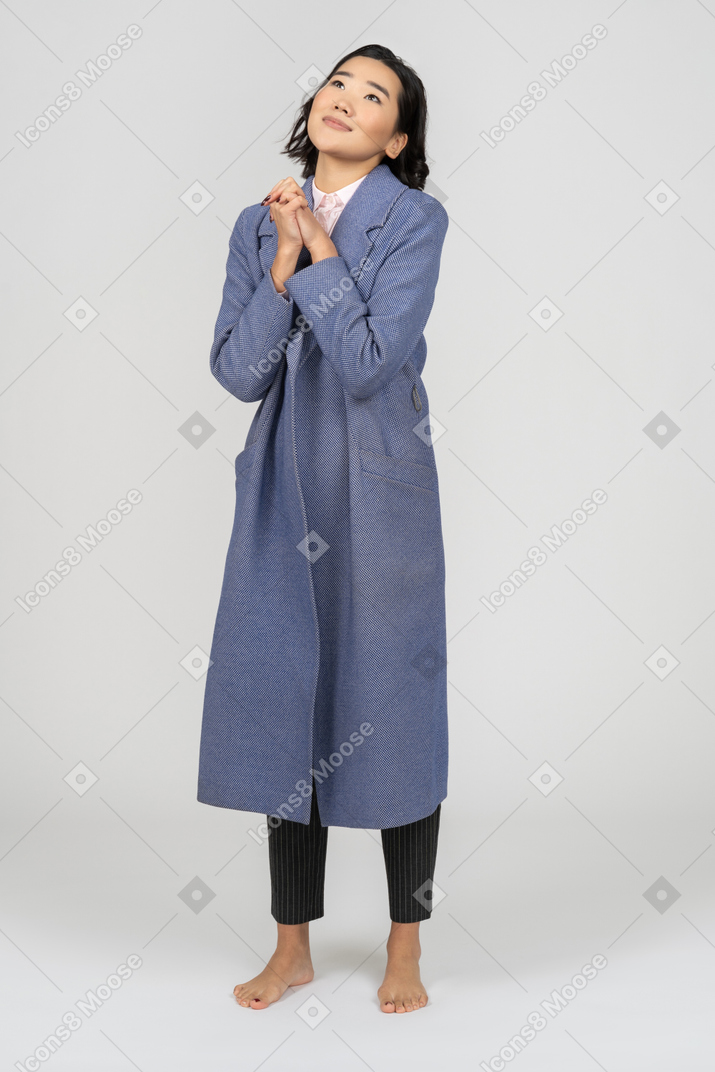 Daydreaming woman in coat with folded hands