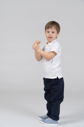 Side view of little boy standing with his arms bent