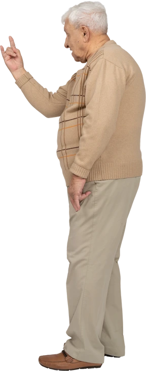 Side view of an old man in casual clothes showing rock gesture