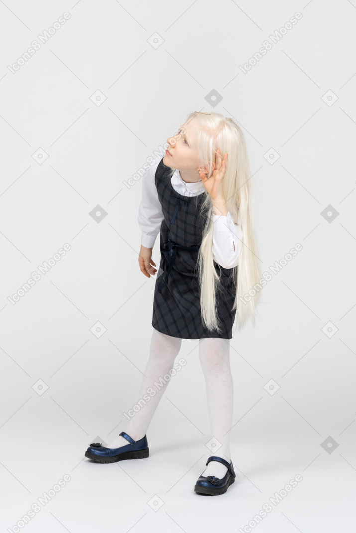 Schoolgirl listening with hand behind ear