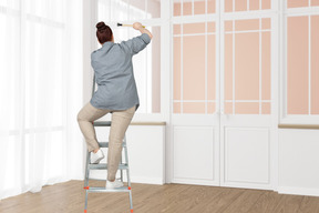 Woman standing on stepladder with hammer