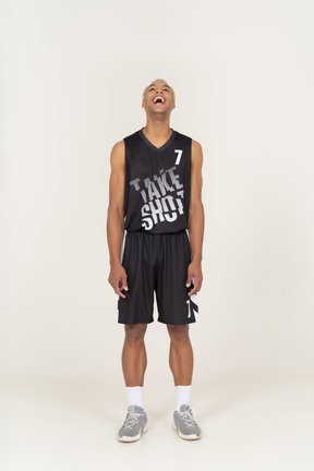 Vista frontal de um jovem jogador de basquete rindo levantando a cabeça