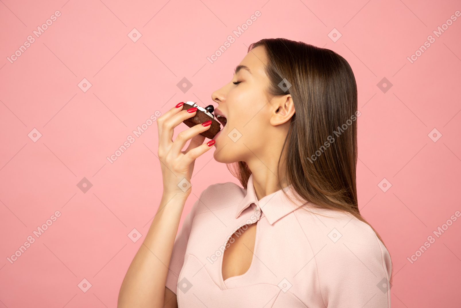 Chica atractiva comiendo un pastel y lamiéndose el dedo.