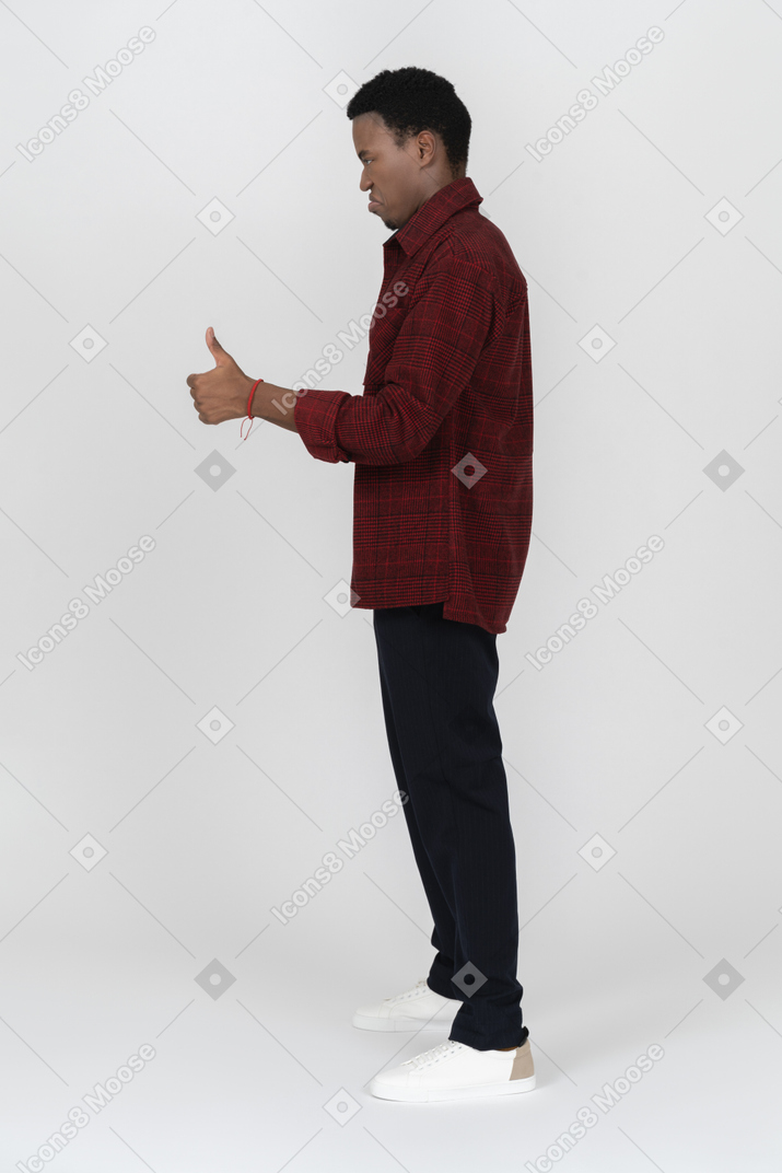 Side view of young man giving thumbs up