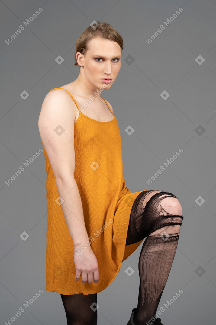 Portrait of a young non-binary person holding up knee in ripped tights