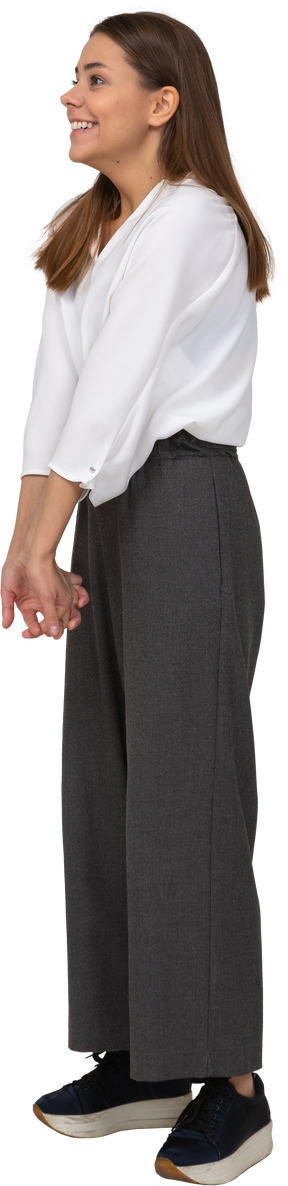 Vue de trois quarts d'une jeune femme souriante en tenue de bureau se tenant la main