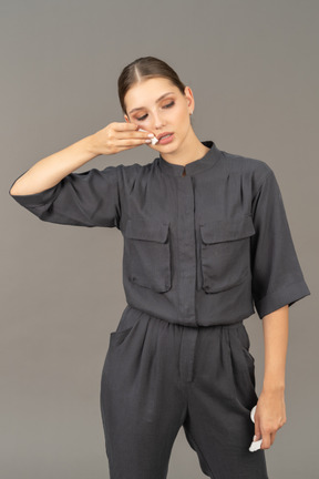 Front view of a young woman in a jumpsuit removing make-up