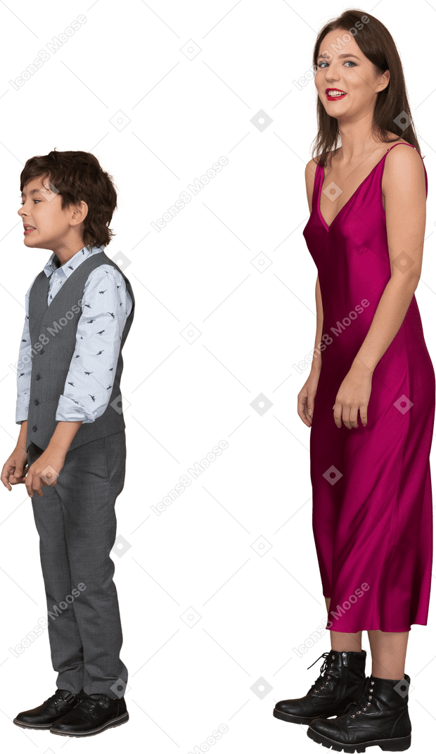 Mujer en vestido rojo mirando a la cámara mientras el niño está de pie cerca