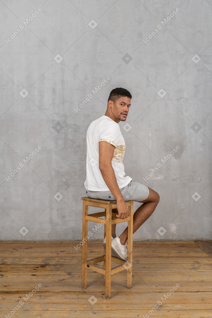 Мужчина сидит на стуле и оглядывается через плечо