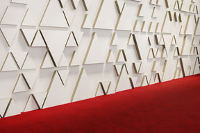 A press wall decorated with triangles and a red carpet below it
