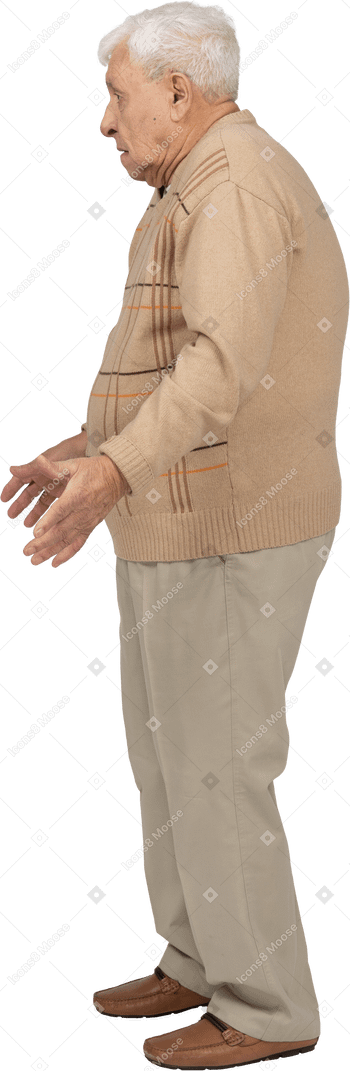 Side view of an old man in casual clothes standing with outstretched arms