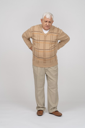 Vista frontal de um velho em roupas casuais em pé com as mãos nas costas
