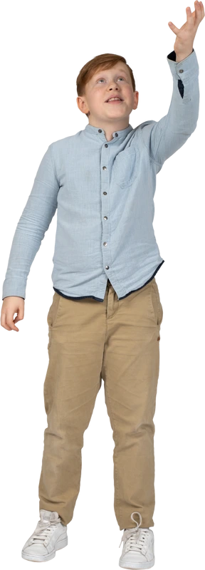 Front view of a cute boy standing with raised arm and looking up