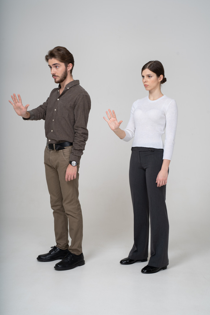 Three-quarter view of a young couple in office clothing outstretching hand
