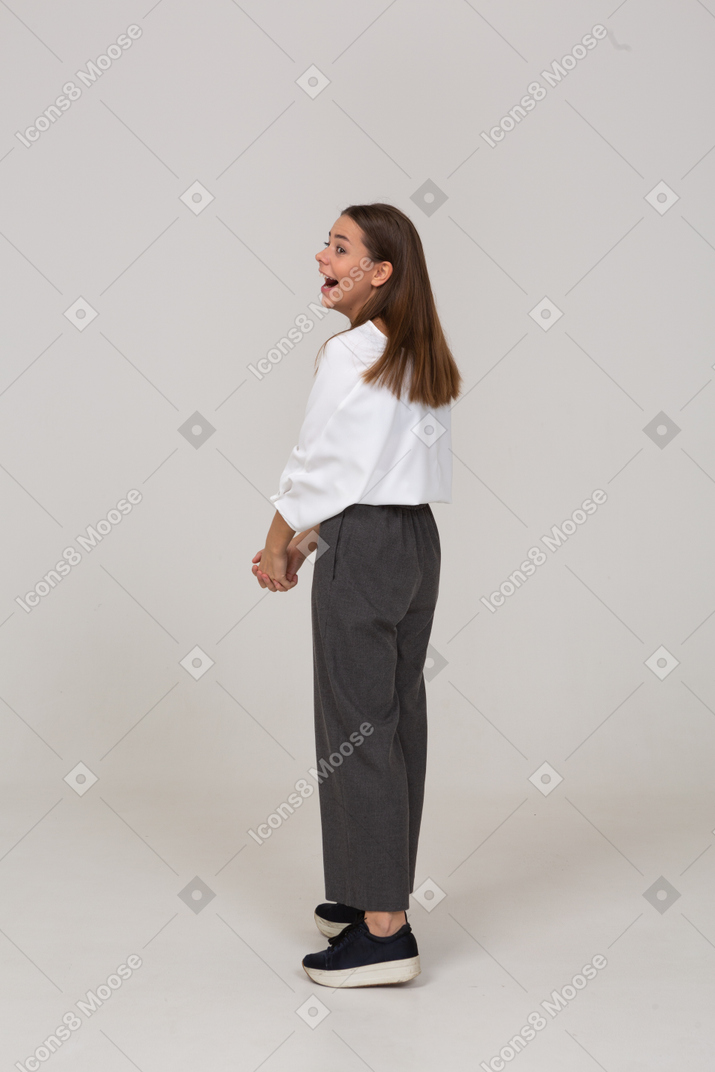 Vista posteriore di tre quarti di una giovane donna che ride in abiti da ufficio