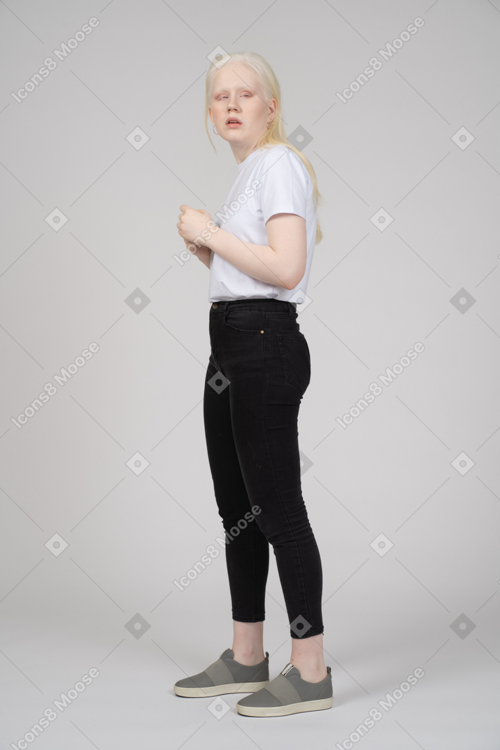 Vue de profil d'une jeune femme en vêtements décontractés regardant par-dessus son épaule
