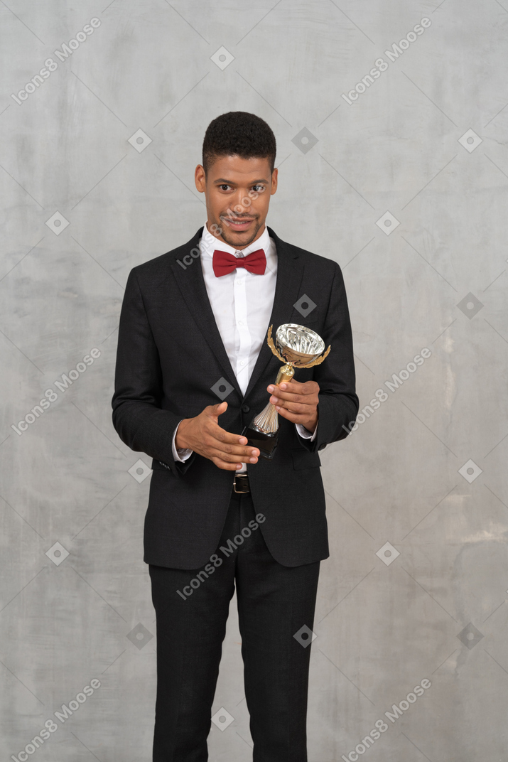 Hombre sonriente con traje sosteniendo un premio
