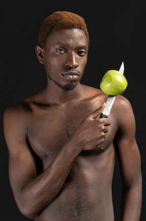 Close-up a man holding aggressively a knife with an apple on it