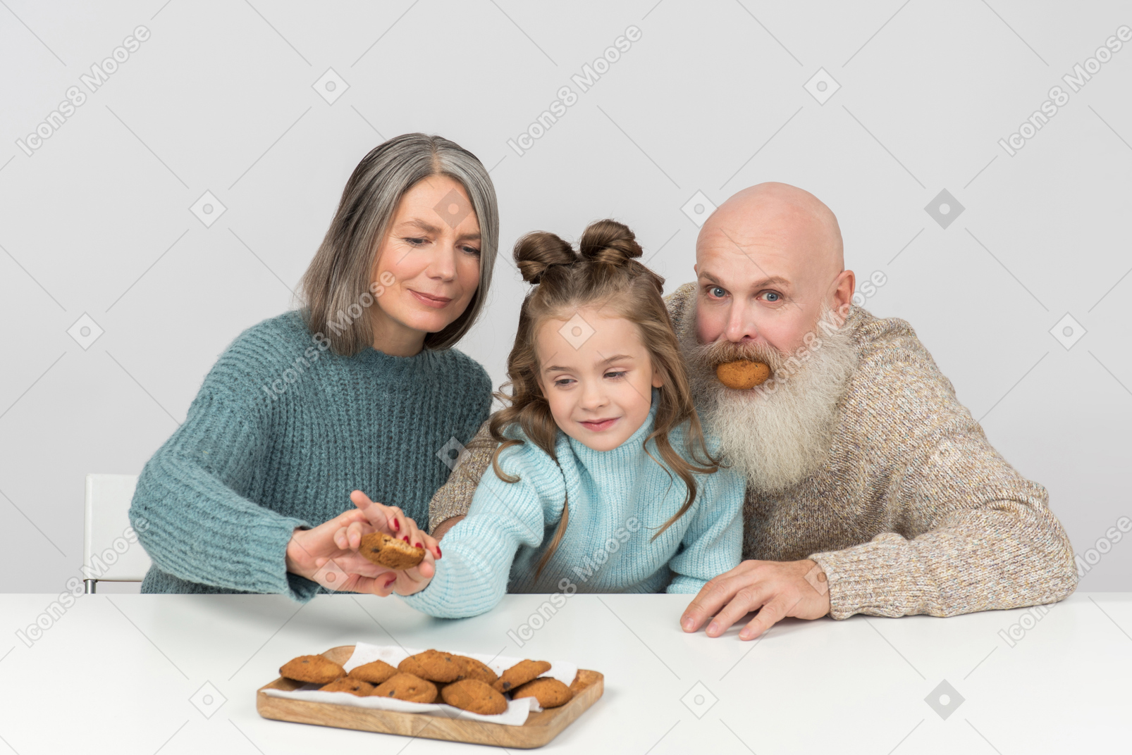 El abuelo no puede dejar de jugar y la abuela evita que el niño tome otra galleta.
