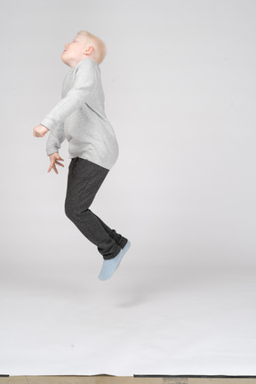 Vista lateral de um menino pulando no ar