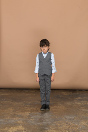 Front view of a boy in suit looking at camera and making faces