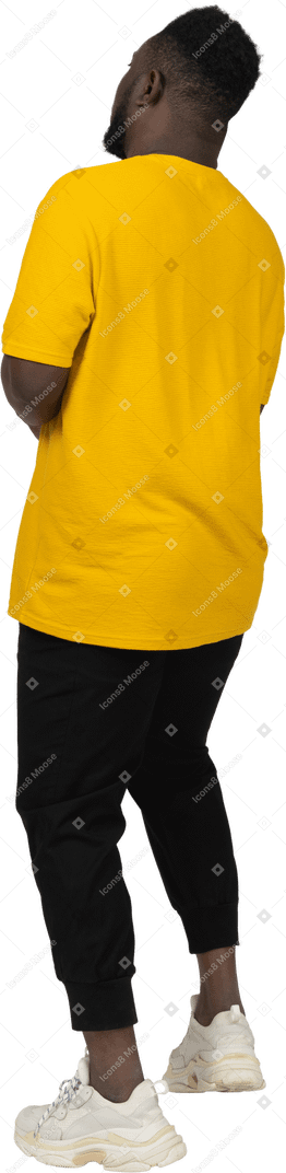노란색 티셔츠를 입은 검은 피부의 젊은 남자의 4분의 3 뒷모습