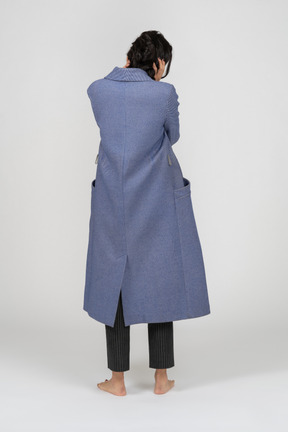 Back view of a woman in coat pulling her hair