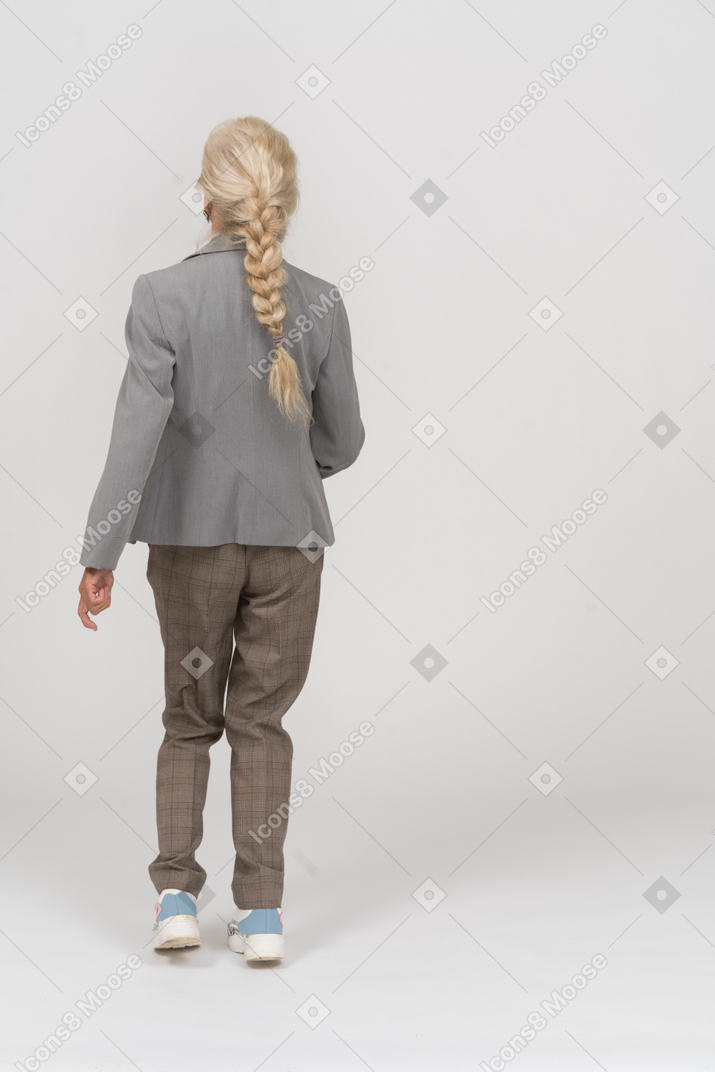 Vista traseira de uma senhora idosa de terno caminhando