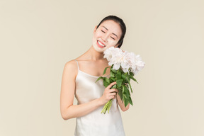 Dreamy young asian woman with facial mask on holding flowers