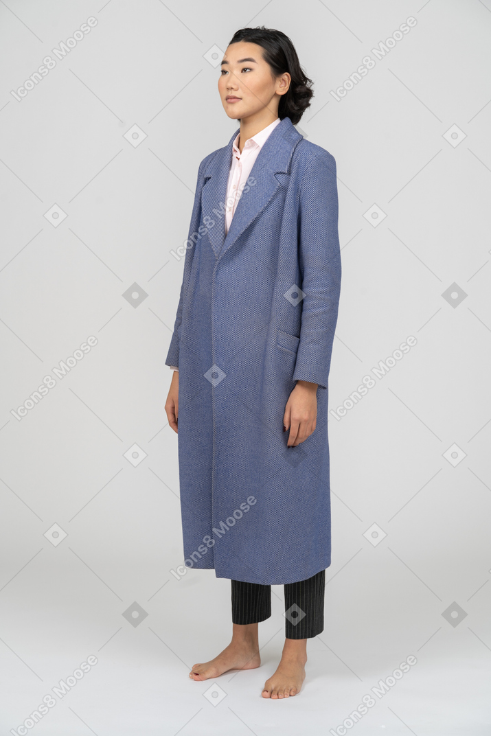 Mulher de casaco azul em pé com os braços nas laterais
