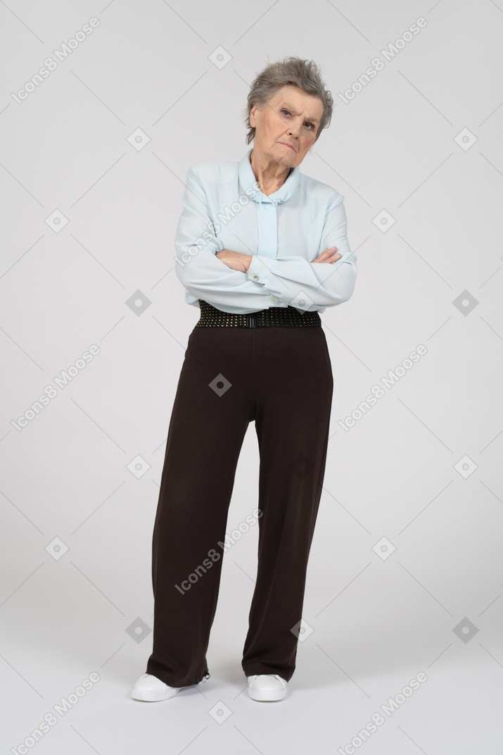 Front view of an old woman frowning suspiciously with folded hands