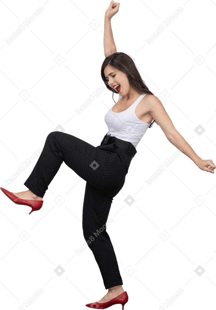 Side view of a happy young female in office clothing dancing and raising hand