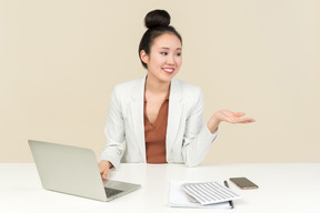 Улыбающийся молодой азиатский офисный работник работает на ноутбуке