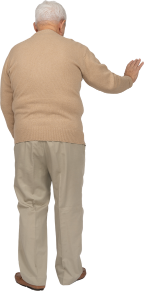 一位穿着休闲服的老人伸出手臂站立的后视图