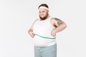 Big guy measuring his waist with cloth ruler