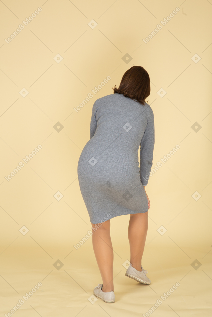 一位身着灰色连衣裙、摸着膝盖的女人的后视图