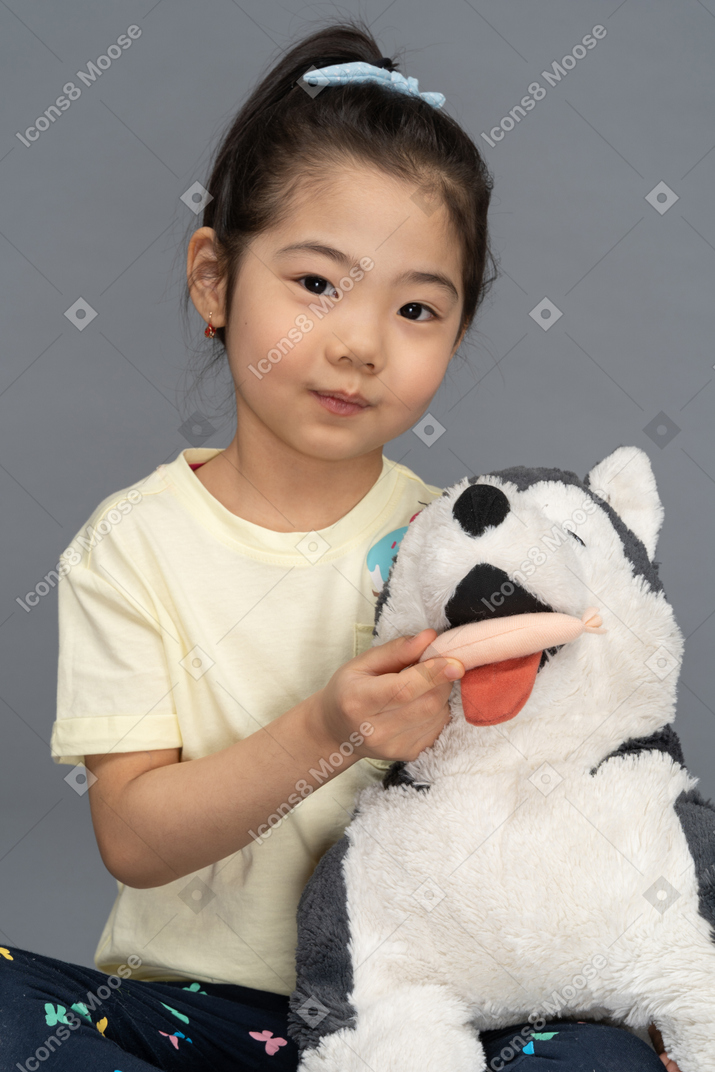 ふわふわの犬のおもちゃを供給する少女