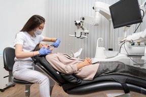 A figura intera di un dentista femminile che gode del processo di esame del suo paziente