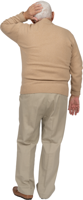 Rear view of an old man in casual clothes standing with hand on head