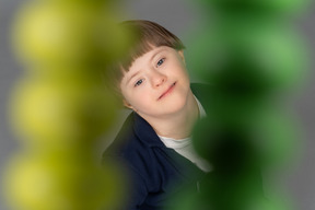 小男孩看着照相机通过黄色和绿色的珠子