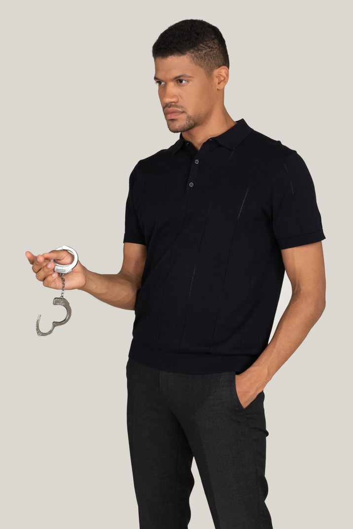 Young man in black pants and t-shirt holding handcuffs