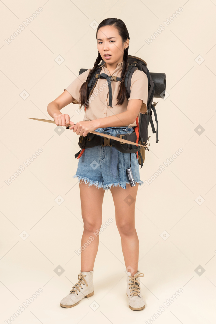 Troubled looking young female hitchhiker holding paper card