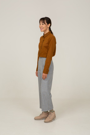 Three-quarter view of a smiling young asian female in breeches and blouse standing still