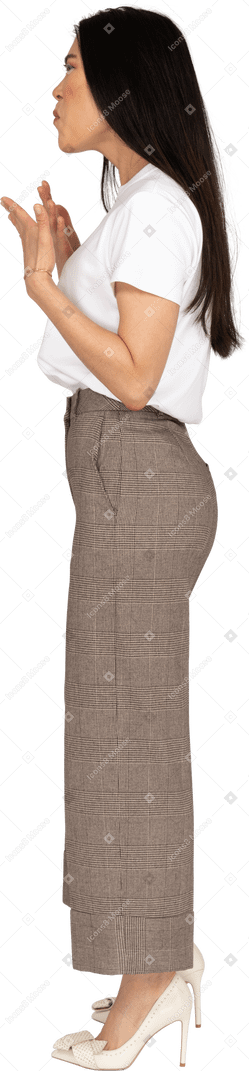 Vista lateral de uma jovem gesticulando descontente, de calça e camiseta