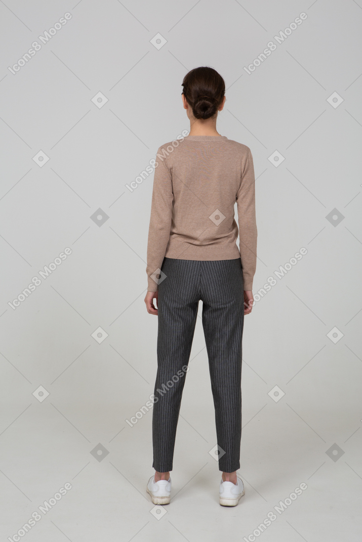 Vista posteriore di una giovane donna in piedi ancora in pullover e pantaloni